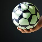 green black ball for handball in the athlete's hand on a black background
